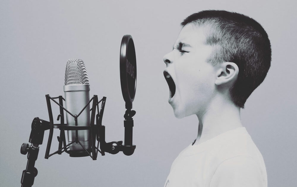 Bambino che parla nel microfono, per raffigurare il Tone of voice marketing